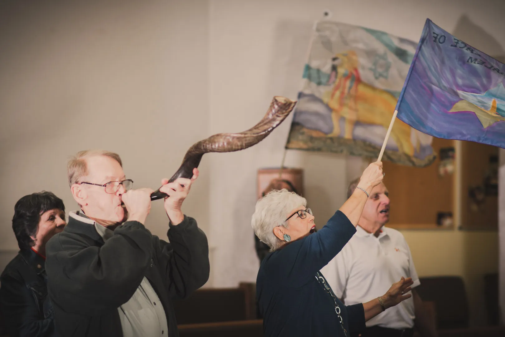 A member of the congregation sounding the shofar while another raises the flag of Israel.