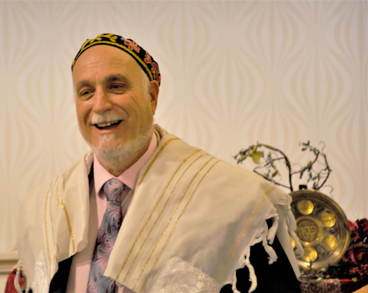 A member in a tallit and kippah, laughing during the service.
