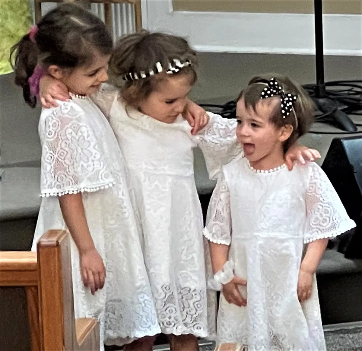Three girls in white lace dresses waiting together before a celebration.