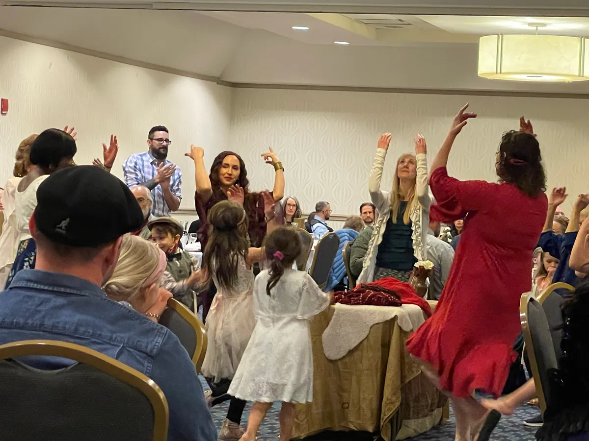 The congregation dancing together with hands raised during worship.